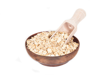 Wooden bowl with oats flakes pile on white background.