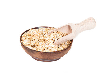 Wooden bowl with oats flakes pile on white background.