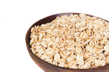 Wooden bowl with oats flakes pile on white background.