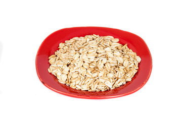 red dish  with oats flakes pile on white background.