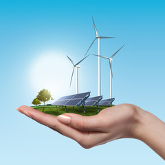 Wind turbines and solar panels in female hand