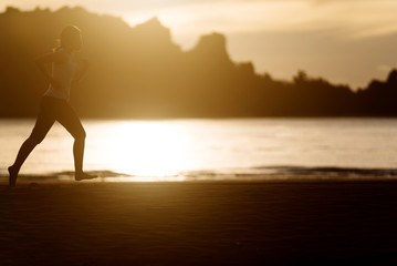 Fototapeta na wymiar Woman running on the beach at sunrise.