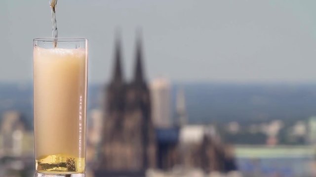 famous german beer called K&ouml;lsch pouring in a beer glas in front of the cologne cathedral