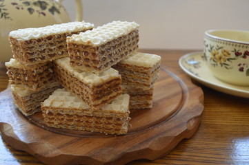 Fototapeta na wymiar Homemade waffles with caramel on wooden board with cup of coffee or tea and kettle 
