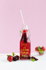 Cherry juice in the bottle on pink background