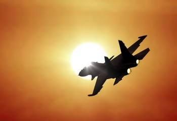 Jet fighter flying under sunset