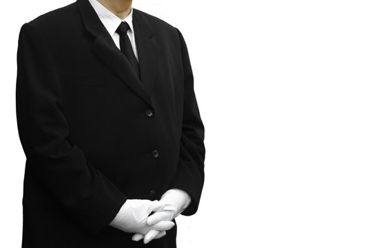 man in black suit standing over white