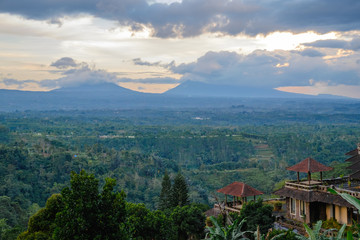 Naklejka premium Soft orange sunset light through grey clouds mist above Batur volcano in Kintamani region, Bali, Indonesia