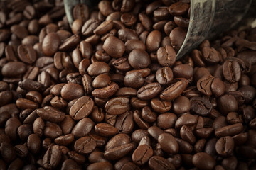 close up pile of coffee bean pour out of the small silver tank w
