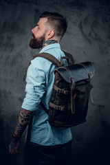 Bearded tattooed backpacker posing in studio.