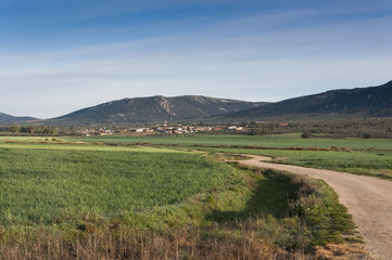 Fototapeta na wymiar Small hamlet in an agricultural landscape in La Mancha, Ciudad Real Province, Spain. In the background can be seen the Toledo Mountains