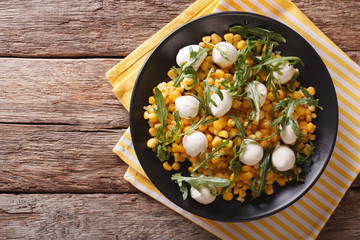 freshly prepared salad of corn, baby mozzarella and arugula closeup. Horizontal top view
