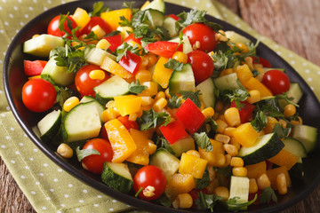 Tasty salad of corn, greens, tomatoes, cucumbers and pepper close-up. Horizontal
