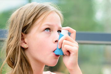 Girl uses an inhaler during an asthma attack - obrazy, fototapety, plakaty