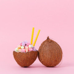 Coconut milk with marshmallow in half coconut on a bright background. Minimal style