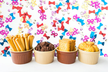 breadsticks, cracker, chocolate cookies and vanilla cookies served in a ceramic dish with colorful background