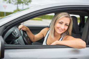 Fototapeta na wymiar Woman driving a car - female driver at a wheel of a modern car,