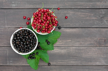 Black and red currants in bowl on rustic wood background