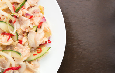 Umai, a dish native to Sarawak, Malaysia made with raw fish marinated in lime juice with onions, ginger, chilli, cucumber and preserved vegetables, served in a white plate on a wooden surface