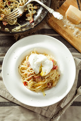 Overhead view of plate of spaghetti Carbonara with poached egg. Rustic styled