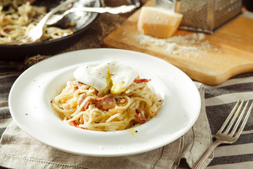 Plate of delicious spaghetti Carbonara with poached egg. Italian food. Rustic styled