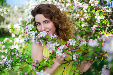 Fototapeta premium portrait of young beautiful woman smelling apple tree branch in
