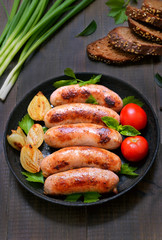 Grilled sausages with onion and fresh tomato in frying pan