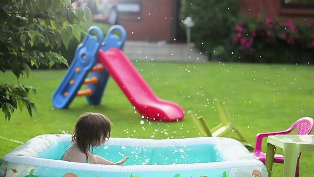 Little girl in a colorful swimming suit jumps into the pool, slow motion