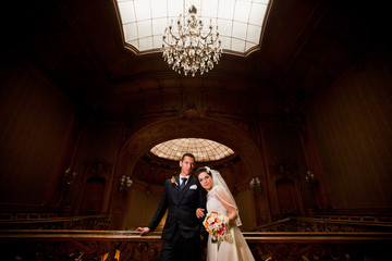 Lovely wedding couple is standing and posing in old hall