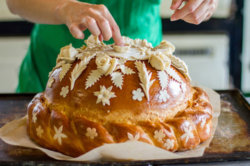 Lady's hand touching decorated pastry. Loaf of bread on tray. Beautiful wedding bread. Stay true to traditions.