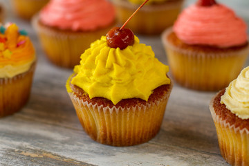 Cupcake with bright frosting. Yellow icing and cherry. Recipe of positive mood. Stay full of energy.