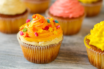 Frosted cupcake on wooden background. Dessert with orange icing. Buttercream and soft dough. Discover the new tastes.