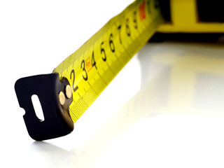 Self-retracting tape measure on white background, closeup, shallow depth of field