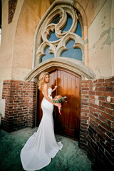 Charming bride in amazing white dress near old door
