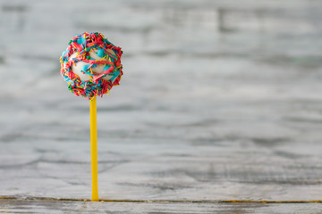 Decorated cake lollipop. Candy with glaze and sprinkles. Flavor of happy life. How to congratulate a kid.