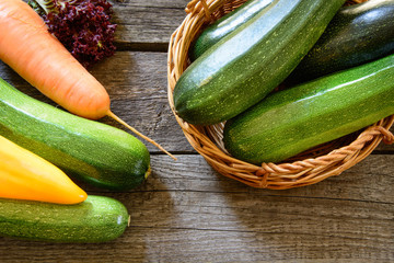 Zucchini in wicker basket with vegetables around. Harvest. View from above.