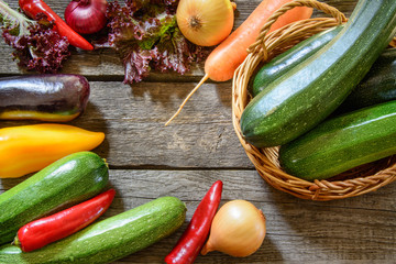 Zucchini in wicker basket with vegetables around. Harvest. View from above.