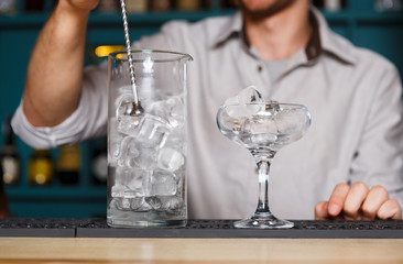 Barman's hands making ice for cocktail