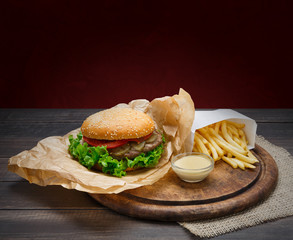 Fast food take away. Hamburger and fries wrapped on wood