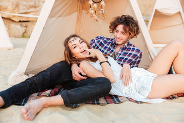 Couple lying and relaxing in teepee on the beach
