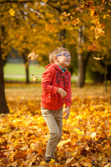Young boy throwing leaves in autumn park