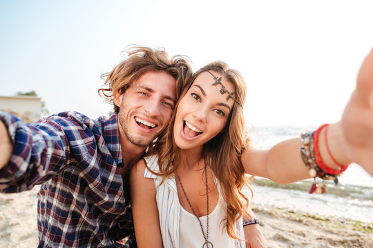 Couple taking selfie and laughing on the beach