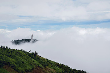 Temple pagoda atop the mist falling around him. Phu Tub Berk.