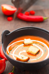 Tomato soup with croutons chili pepper and garlik on a wooden table