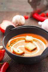 Tomato soup with croutons chili pepper and garlik on a wooden table