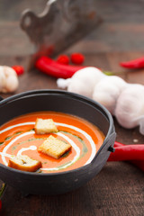 Tomato soup with croutons chili pepper and garlik on a wooden table