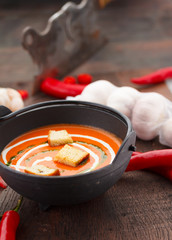 Tomato soup with croutons chili pepper and garlik on a wooden table