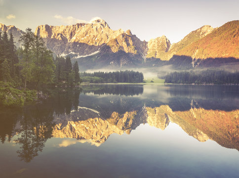 Fototapeta Jezioro alpejskie  o świcie,pięknie oświetlone szczyty gór,kolorystyka retro,vintage        