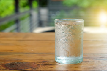 Glass water with drops on glass places on wooden table.