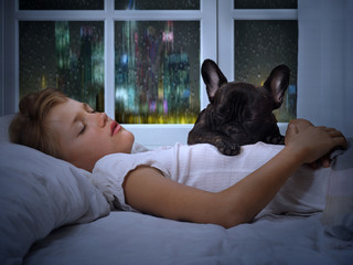 The young girl the teenager and a dog sleeping in the bed. Sound sleep, night, rain outside the window